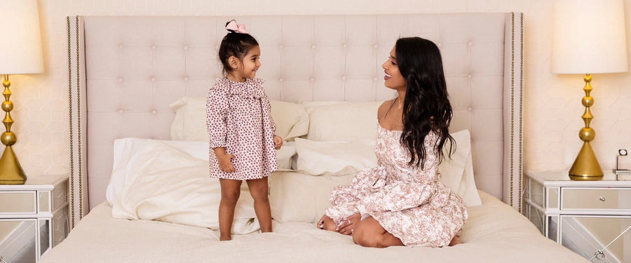 Mother and daughter sitting on a bed, looking at each other.